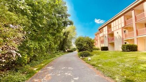 A pathway leading to a building with balconies and a well-maintained lawn.
