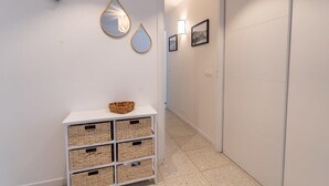 A hallway with white walls, a white console table with baskets, and wall-mounted mirrors and picture frames. - Bel appt 6 p avec piscine, parking gratuit et tennis 109 (Le Touquet-Paris-Plage)