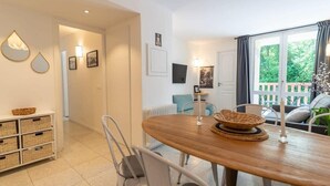 A dining area with a wooden table and chairs, a buffet counter with baskets, and a view of the outdoors through a sliding glass door. - Bel appt 6 p avec piscine, parking gratuit et tennis 109 (Le Touquet-Paris-Plage)