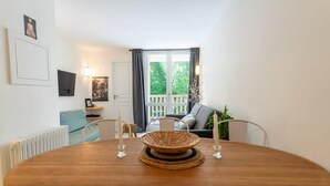 A dining area with a round wooden table, two candles, and a woven basket centerpiece. - Bel appt 6 p avec piscine, parking gratuit et tennis 109 (Le Touquet-Paris-Plage)