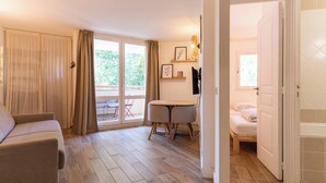 A room with a sofa, a dining table with chairs, a bed, and a sliding glass door leading to an outdoor area. - Appt pour 4 pers avec piscine couverte tennis et parking gratuit 227 (Le Touquet-Paris-Plage)
