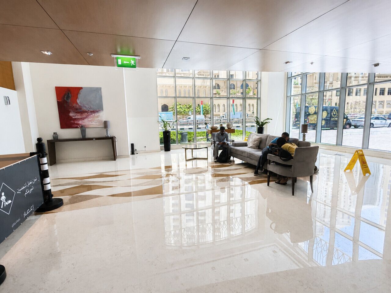 Eine moderne Lobby mit Empfangsschalter, Sitzgelegenheiten und großen Fenstern mit Blick auf die Straße.