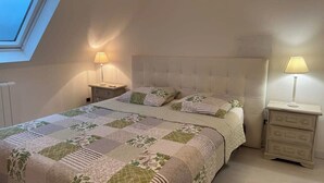 Une chambre à coucher avec un grand lit, deux tables de chevet et une lucarne.
