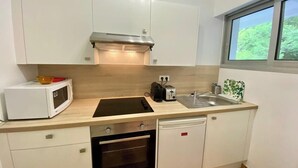 A compact kitchen with white cabinets, a microwave, a toaster, a sink, and a dishwasher.