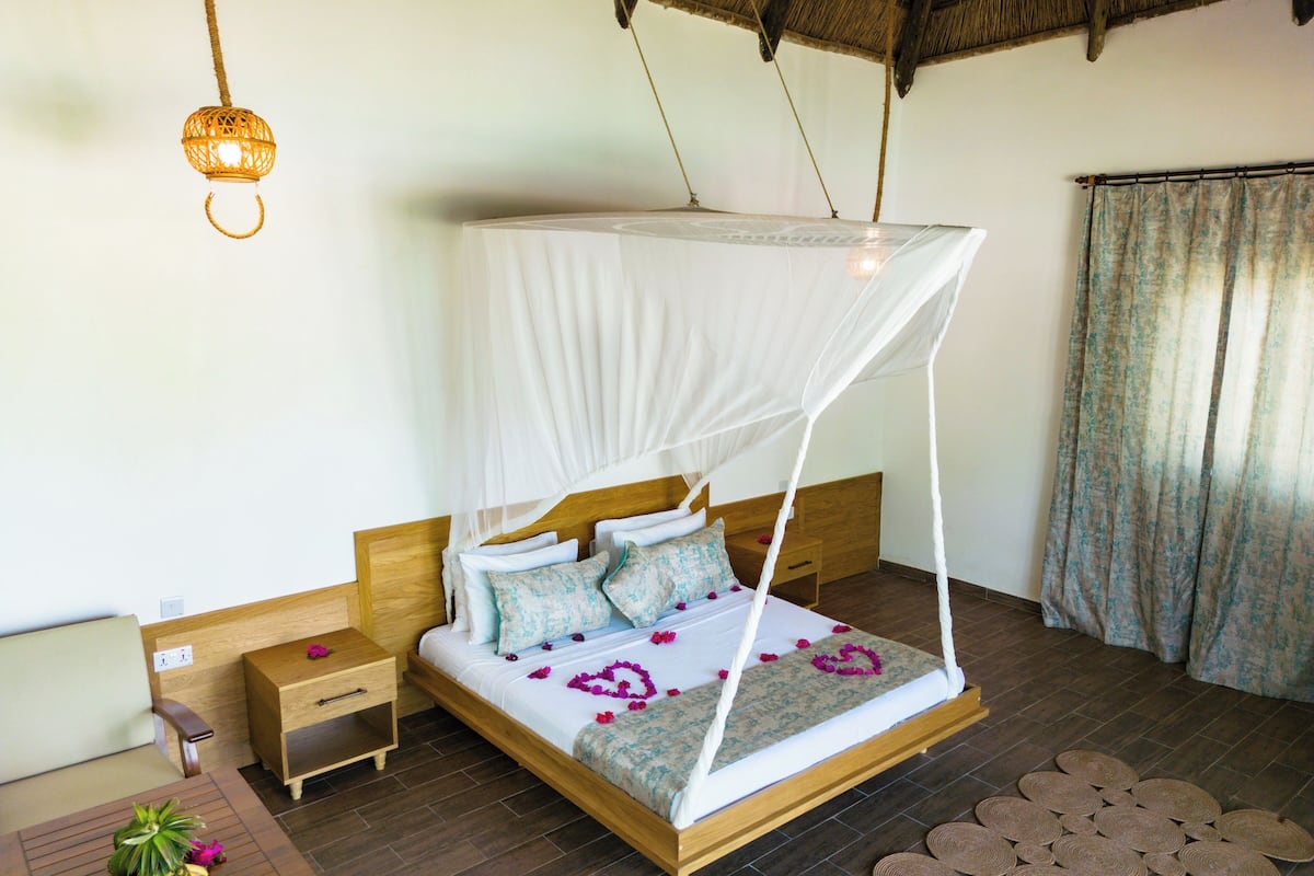 A bed with a canopy, wooden headboard, bedside table, and a small nightstand.