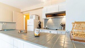 A modern kitchen with white cabinets, a stainless steel countertop, a built-in microwave, and a wooden drying rack.