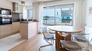 Eine moderne Küche mit Essbereich, großen Fenstern und Blick ins Freie.