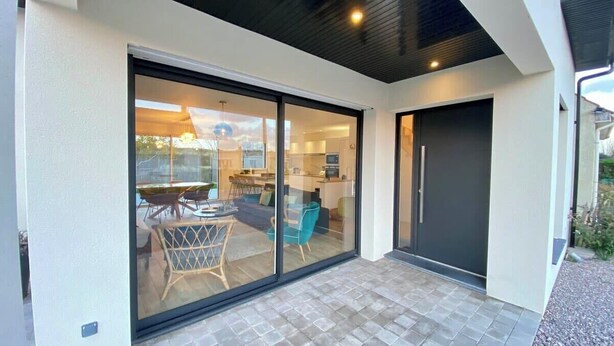 A modern house with a sliding glass door leading to a patio with outdoor furniture. - Superb cottage for 4 people with views of the dunes (Merlimont)