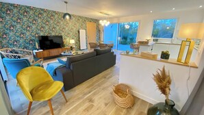 A modern living room with a sofa, chairs, a TV, and a dining area. - Superb cottage for 4 people with views of the dunes (Merlimont)