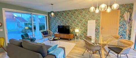 A living room with a sofa, chairs, a TV, and a dining table.