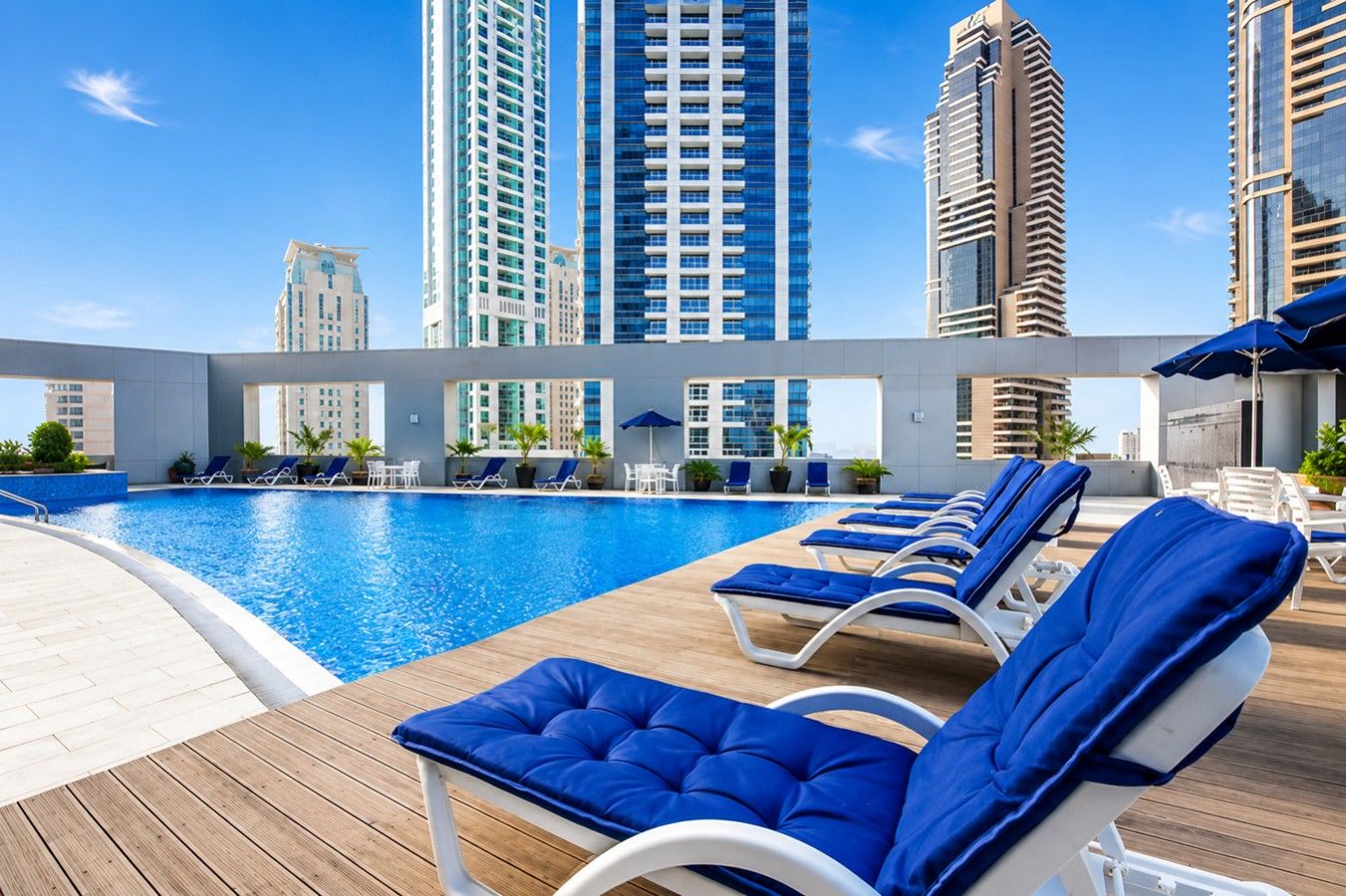 A rooftop pool area with lounge chairs and a clear view of surrounding high-rise buildings.