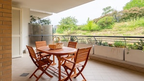 A covered outdoor patio with a round wooden table and chairs, a wicker basket, and a view of greenery and hills. - Bonum Vitae in Rome With 1 Bedrooms and 1 Bathrooms (Rome)