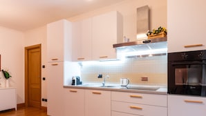 A modern kitchen with white cabinets, a stainless steel oven, and a wooden floor. - Bonum Vitae in Rome With 1 Bedrooms and 1 Bathrooms (Rome)