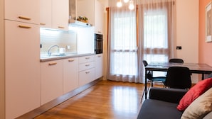 A modern kitchen with white cabinets, a built-in oven, and a dining area with a table and chairs. - Bonum Vitae in Rome With 1 Bedrooms and 1 Bathrooms (Rome)