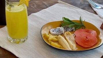 A table with a glass of yellow drink, a plate with fruits and a star-shaped garnish.