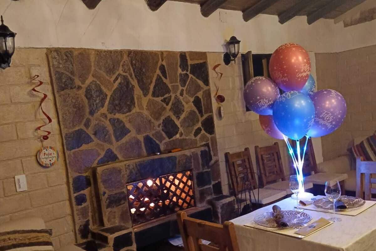 A dining area with a stone wall, wooden beams, and a table set for a meal.