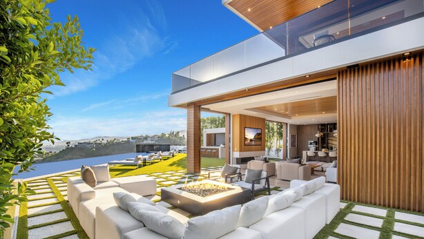 A modern outdoor living area with a fire pit, white sofas, and a view of a body of water.