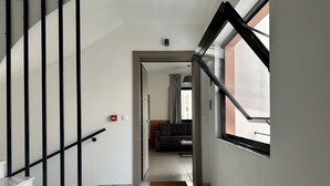 Eine moderne Treppe mit Marmorstufen und schwarzen Geländern, die zu einem Wohnbereich mit Sofa und Fenster führt.