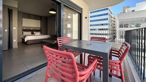 Ein Balkon mit Tisch und Stühlen, einem Bett und Blick auf die Stadt.