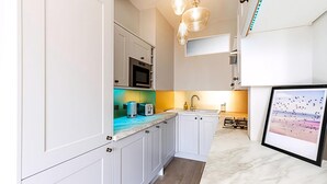 A modern kitchen with white cabinetry, a microwave, a toaster, and a sink. - Lovely Bishops Park Flat (London)