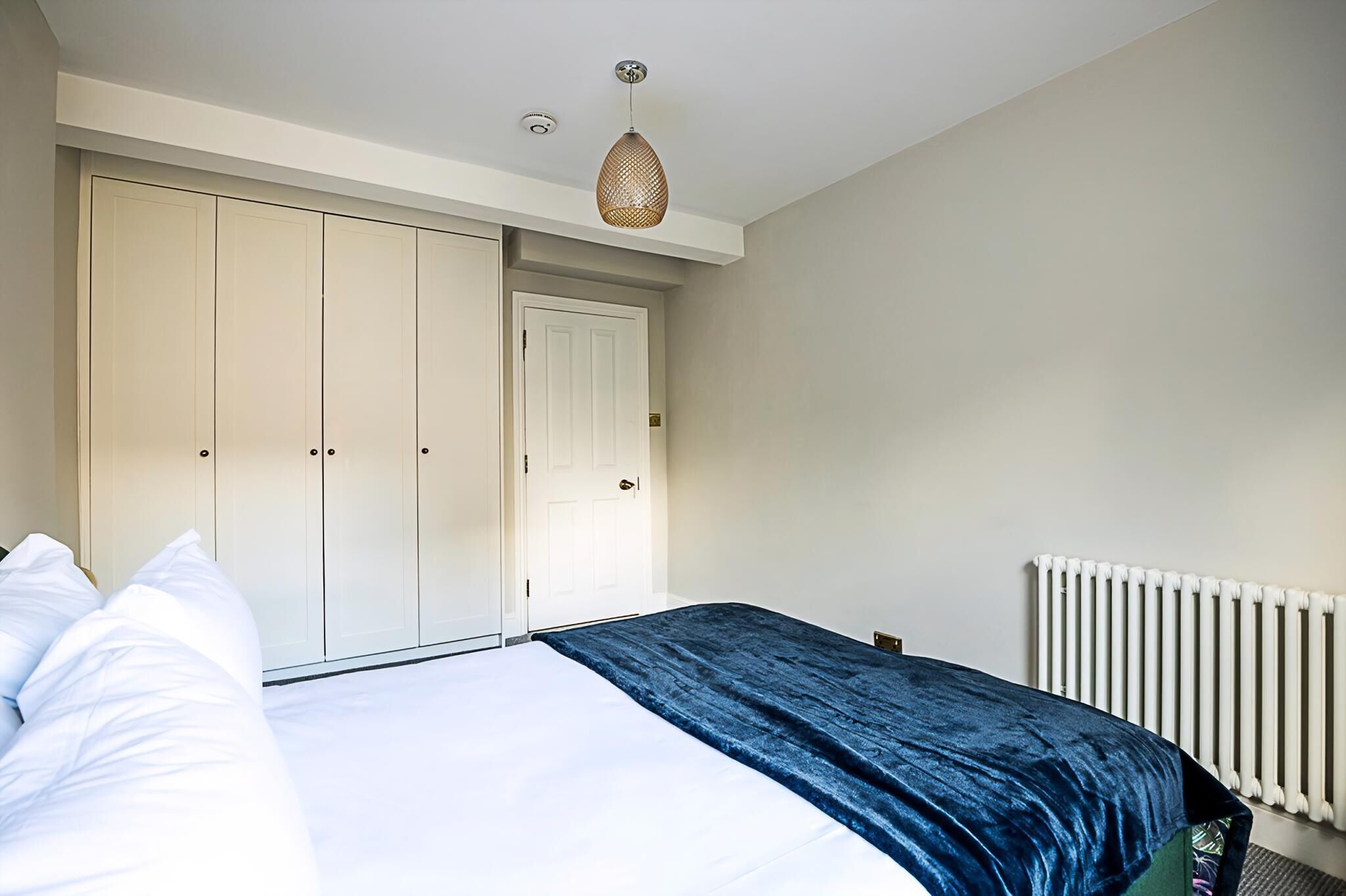 A bedroom with a bed, a wardrobe, and a radiator.
