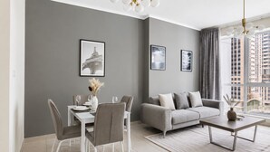 Una sala de estar moderna con un sofá gris, una mesa de comedor, sillas, una mesa baja y obras de arte en las paredes.