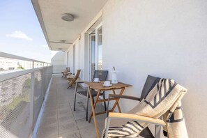 A balcony with a table and chairs, a white wall, and a metal railing. - Warsaw | Przejazd 2 | Spacious Apartment | Air Conditioning (Warszawa)