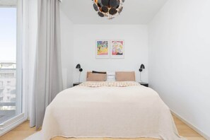 A bedroom with a large bed, two wall-mounted lamps, and two framed artworks. - Warsaw | Przejazd 2 | Spacious Apartment | Air Conditioning (Warszawa)