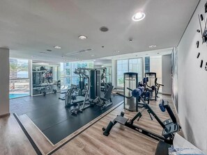 Une salle de sport équipée de divers appareils d’exercice, dotée de grandes fenêtres et offrant une vue sur l’extérieur.