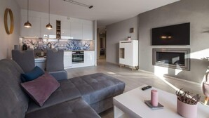 Ein modernes Wohnzimmer mit einem grauen Sofa, einem weißen Couchtisch und einem an der Wand befestigten Flachbildfernseher.