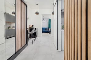 A modern kitchen with a dining area, featuring a kitchen island, pendant lights, and a view into a living space.