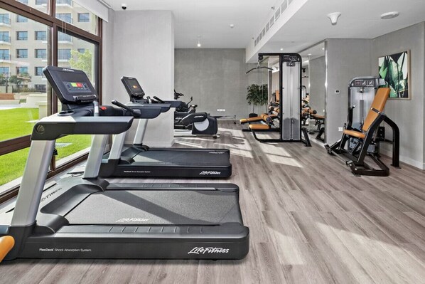 A gym with treadmills, weight machines, and a mirror.