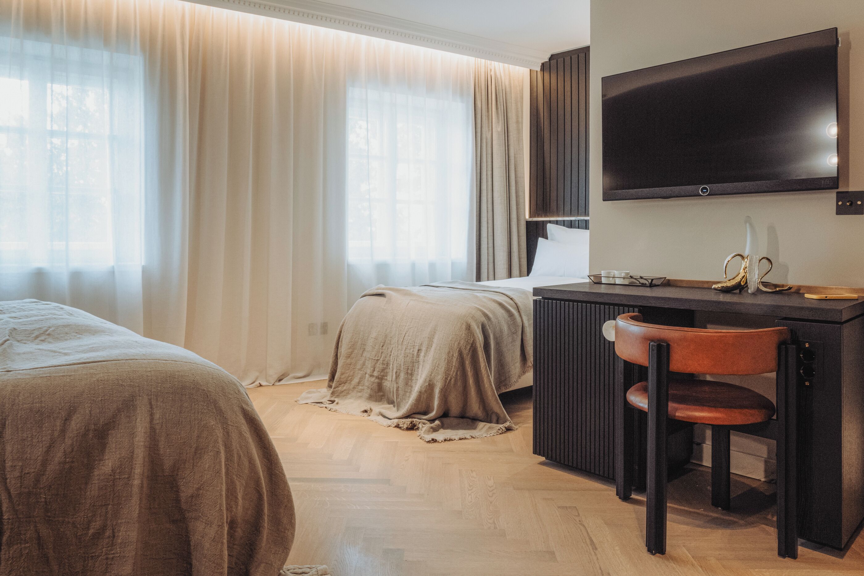 A hotel room with a bed, a desk with a chair, a television, and curtains.