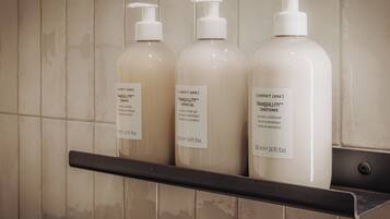 Trois bouteilles de produits TRANQUILLITY™ sont posées sur une étagère, adossées à un mur recouvert de carreaux.