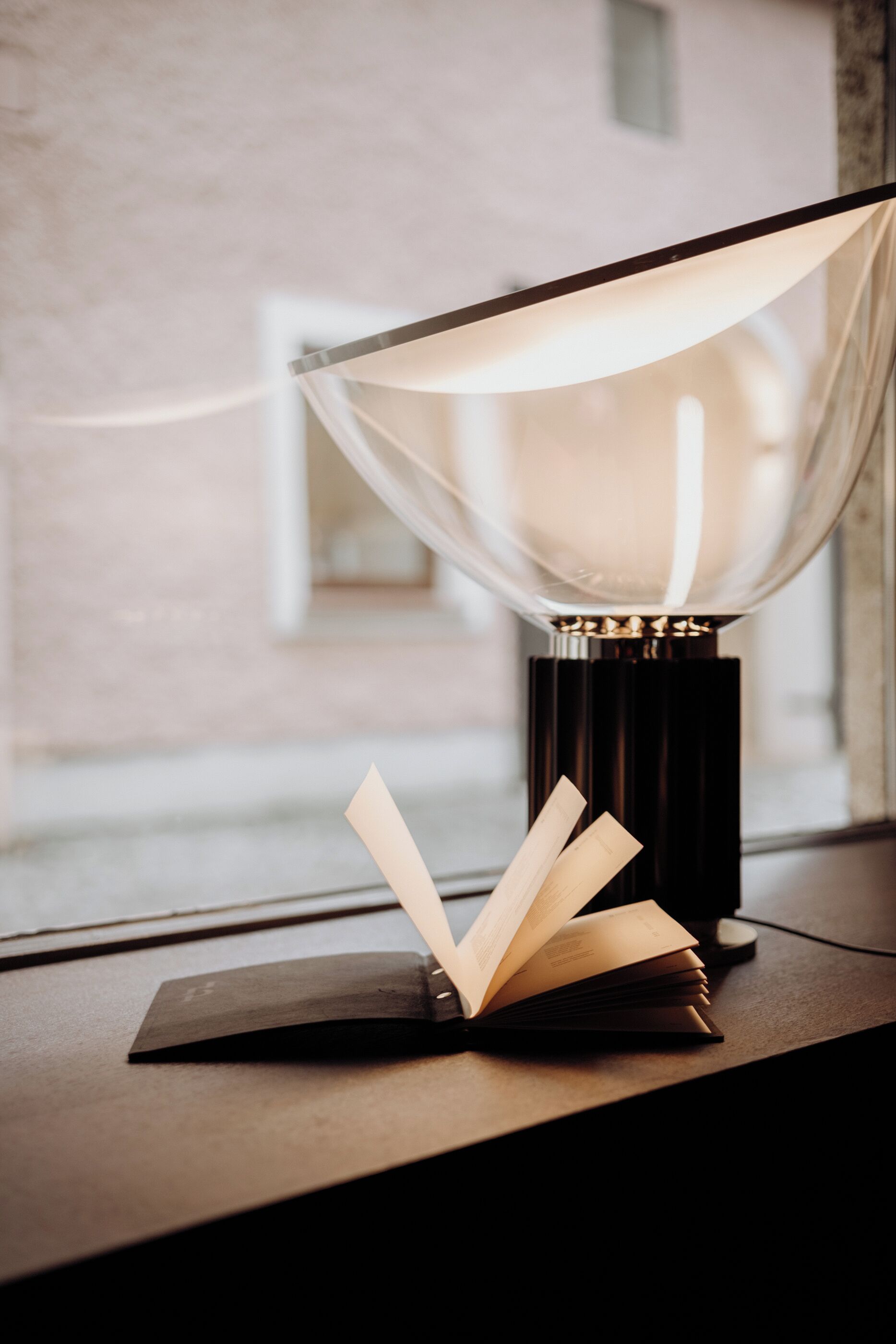 A table lamp with a clear shade and a book on it.