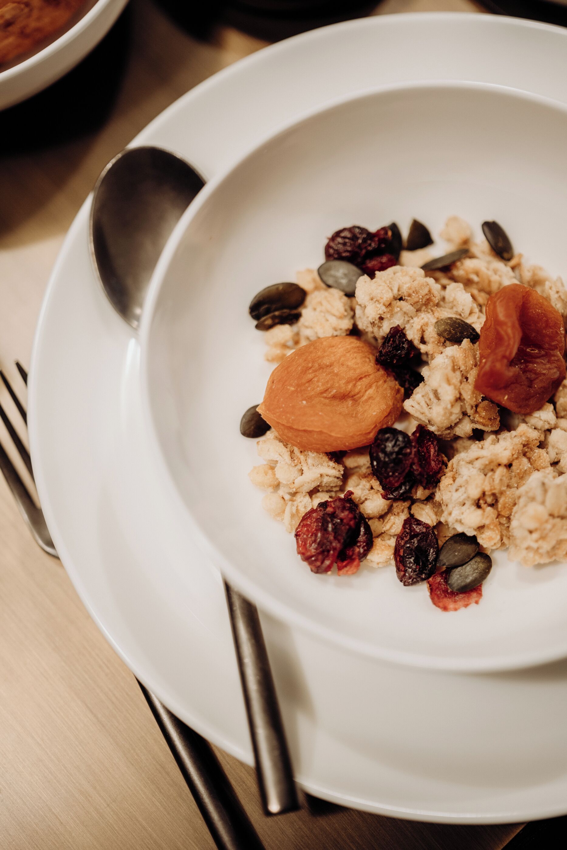 Un bol de porridge amb fruites seques i fruits secs damunt d'un plat blanc.