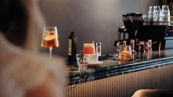 Eine Bar mit Tresen, Gläsern, einer Flasche und einer Kaffeemaschine.