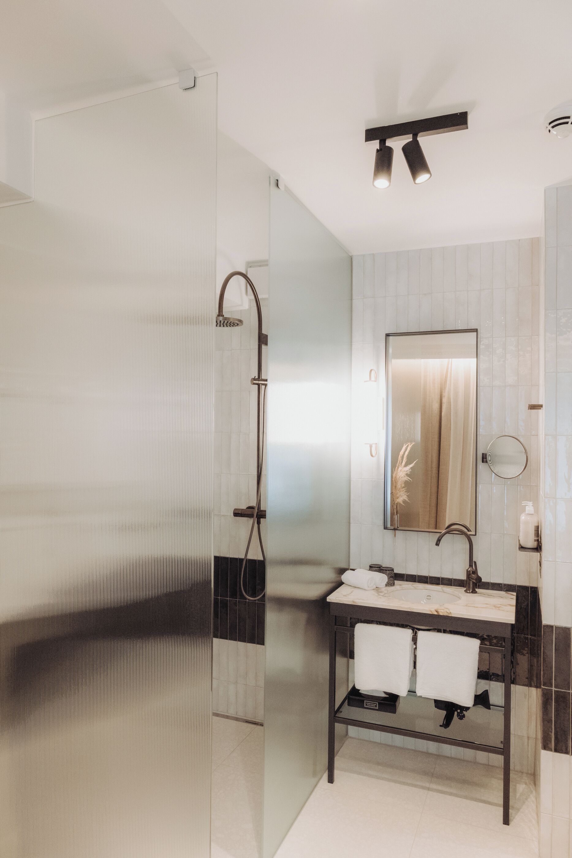 Un baño moderno con cabina de ducha de vidrio, lavabo de mármol y un espejo grande.