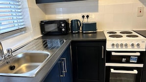 Uma cozinha compacta com pia, micro-ondas, torradeira e fogão.