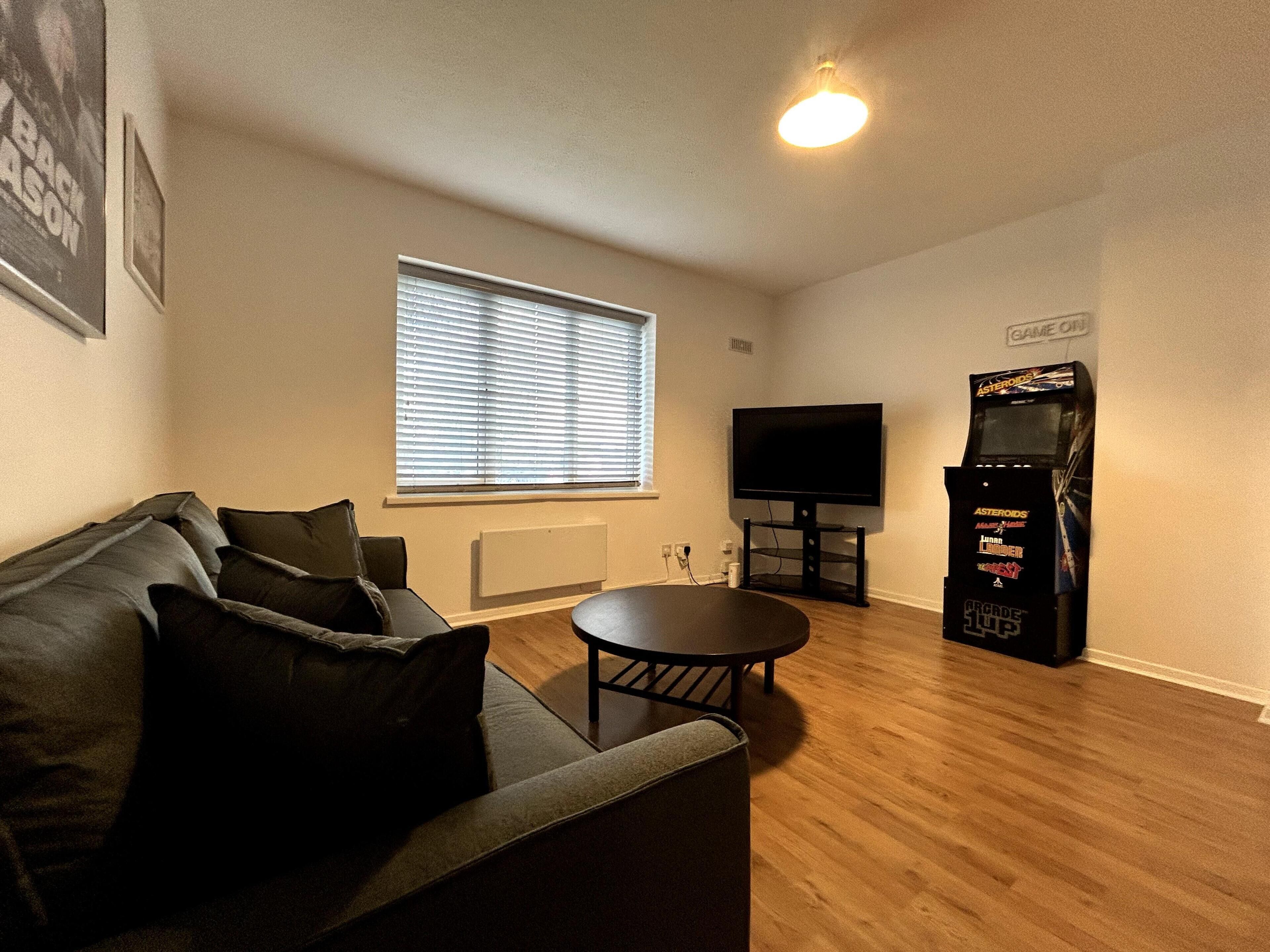 A living room with a sofa, a television, and a gaming console.