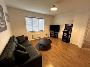 Ein Wohnzimmer mit einer Couch, einem Couchtisch, einem Fernseher und einer Spieluhr.