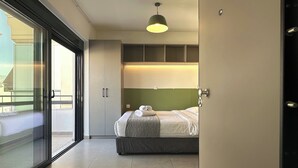 Een moderne slaapkamer met een bed, een glazen deur naar een balkon en een hanglamp boven het bed.