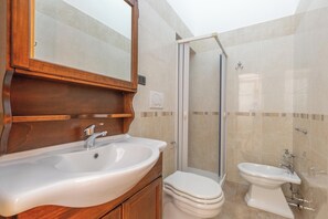 A bathroom with a wooden vanity, a sink, a toilet, and a shower enclosure. - 3922 Villino Gioiellino by Barbarhouse (Melendugno)
