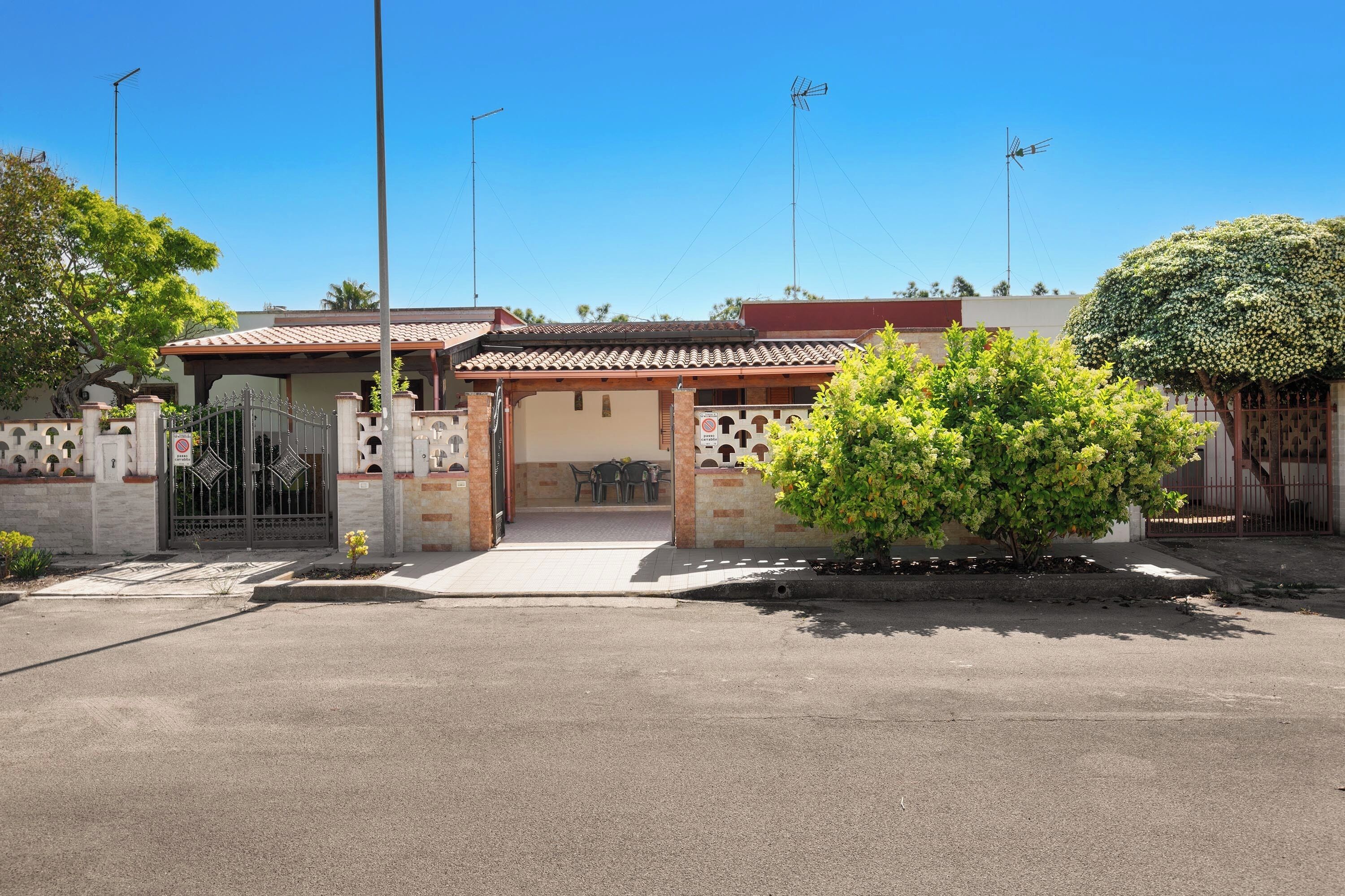 A residential building with a gated entrance, a covered patio, and a well-maintained garden.