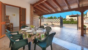 An outdoor patio with a wooden pergola, a table set for dining, and chairs. - 3922 Villino Gioiellino by Barbarhouse (Melendugno)