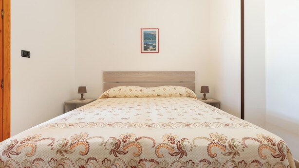 A bedroom with a bed, two bedside tables, a nightstand, a framed picture on the wall, and a wooden door. - 3922 Villino Gioiellino by Barbarhouse (Melendugno)
