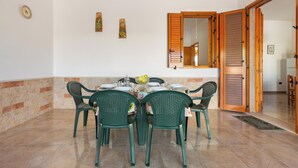 A dining area with a table set for four, surrounded by green chairs, a wooden door, and a wall-mounted mirror. - 3922 Villino Gioiellino by Barbarhouse (Melendugno)