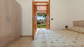 A bedroom with a bed, a wardrobe, and an open door leading to an outdoor area. - 3922 Villino Gioiellino by Barbarhouse (Melendugno)