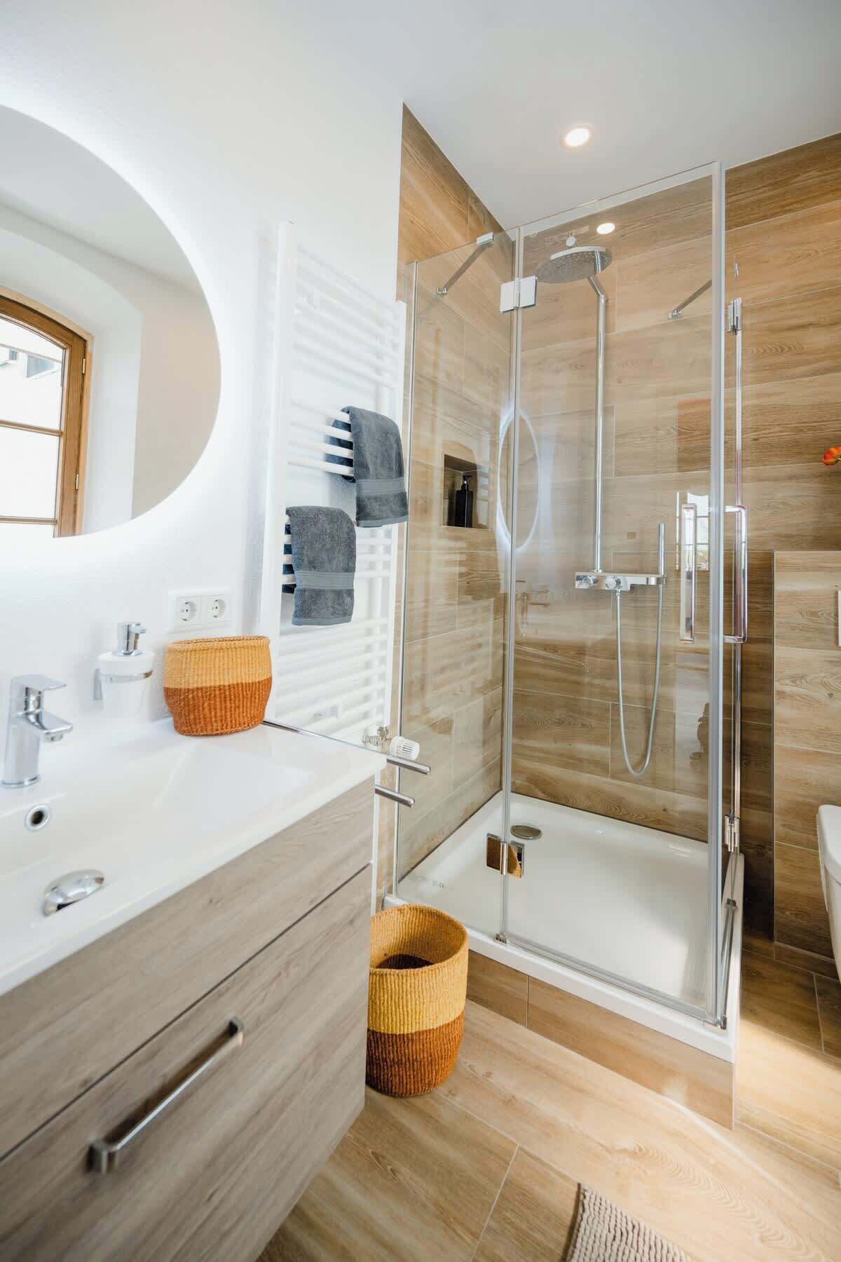 Une salle de bain moderne avec une douche à parois de verre, un meuble-lavabo en bois et un grand miroir.