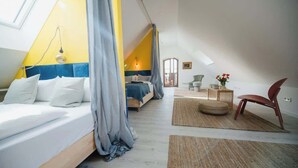 A bedroom with a sloped ceiling, a bed with white bedding, a wooden headboard, and a view of the adjacent room.
